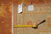 Load image into Gallery viewer, A vintage-style area rug with a beige, orange, and pink pattern, shown with a yellow tape measure and size tag.
