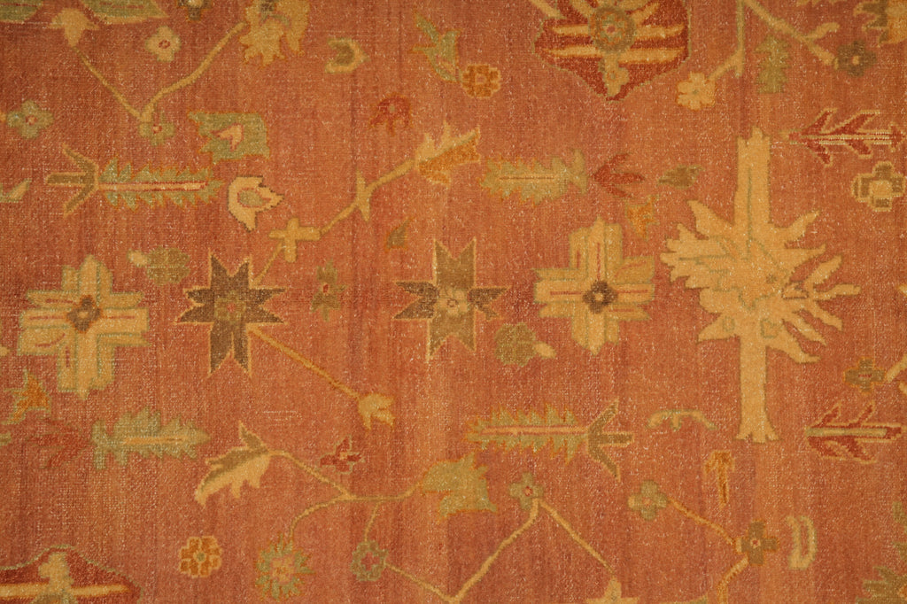 A close-up of a patterned textile or rug in warm rust orange with beige, olive green, and muted red floral and geometric motifs.