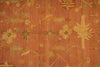 Load image into Gallery viewer, A close-up of a patterned textile or rug in warm rust orange with beige, olive green, and muted red floral and geometric motifs.