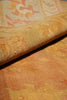 Load image into Gallery viewer, A close-up of a folded textile or rug showing a warm abstract pattern in golden yellow, peach, and orange tones.