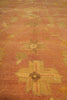 Load image into Gallery viewer, A close-up view of a textured area rug with a warm terracotta orange base and faded yellow and beige floral motifs.