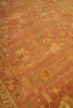 Load image into Gallery viewer, A close-up view of a traditional oriental rug with a warm terracotta orange base and an intricate floral pattern in muted beige, olive green, and rust red.