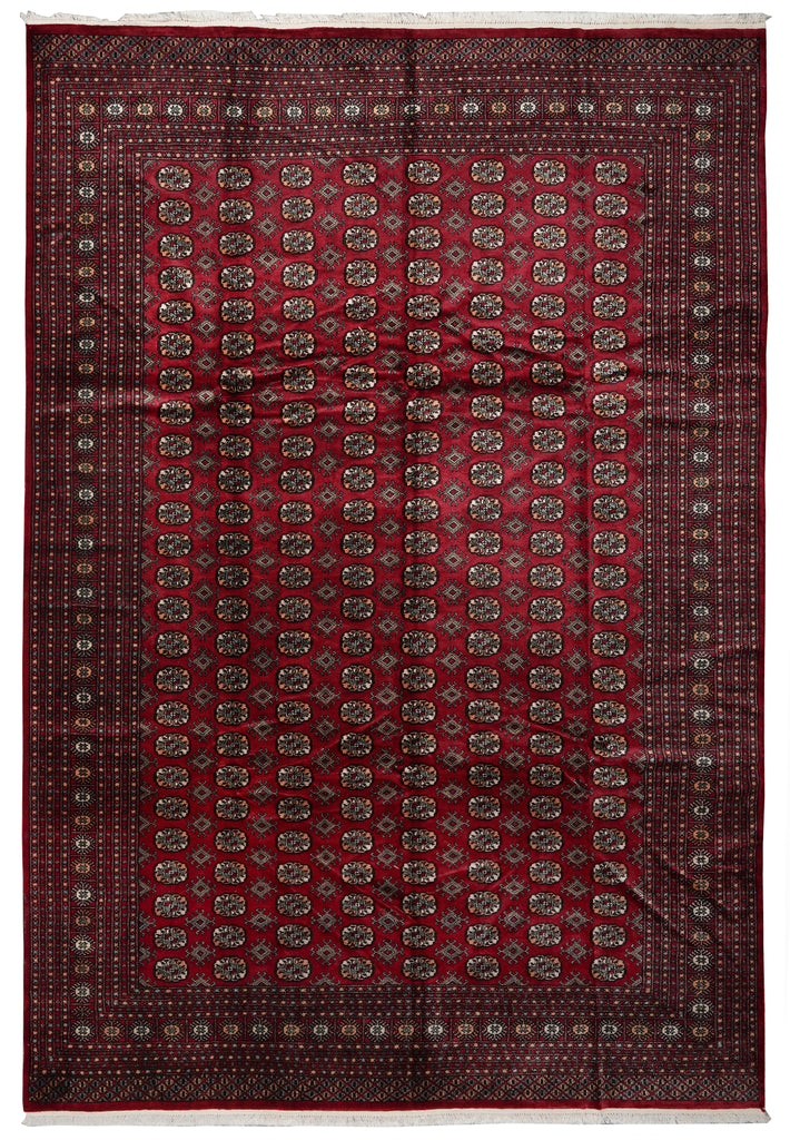 A traditional oriental area rug with a deep red field, detailed geometric borders, and small central motifs in beige, brown, and muted blue.