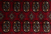 Load image into Gallery viewer, A close-up of a red patterned rug featuring repeating geometric medallion motifs in beige, black, blue, and red.