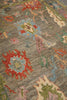 Load image into Gallery viewer, A close-up of a traditional hand-knotted area rug with a textured gray-brown base and intricate floral motifs in red, light blue, green, pink, and beige.