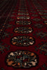 Load image into Gallery viewer, A close-up view of a traditional patterned rug with a deep red background and repeating geometric medallion motifs in beige, black, and muted blue-gray.