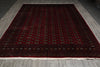 Load image into Gallery viewer, A large rectangular area rug with a deep red field, intricate geometric patterns, and a dark border, laid out on a gray wood-look floor.