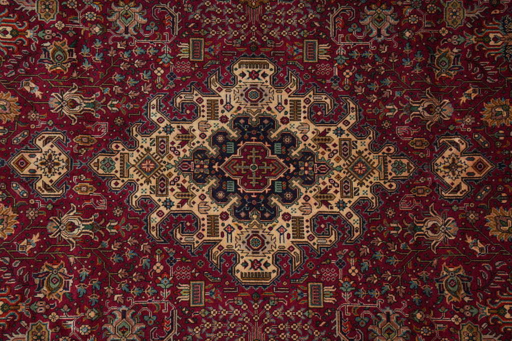 A traditional Persian-style area rug with a deep red background and an intricate central medallion pattern in beige, navy, and gold.