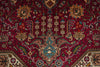 Load image into Gallery viewer, A close-up of a traditional Persian-style area rug with a deep red field, featuring a central medallion and intricate floral motifs in beige, blue, green, and brown.
