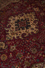 Load image into Gallery viewer, A close-up view of an intricate Persian-style area rug with a deep red field, a large beige central medallion, and detailed floral motifs in black, green, and blue.