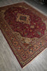 Load image into Gallery viewer, A traditional oriental area rug with a deep red central field, intricate floral motifs, and a detailed multi-colored border, shown laid out on a gray wood floor.