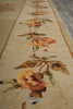 Load image into Gallery viewer, A close-up view of a long floral runner rug in warm beige, orange, brown, and muted green tones, laid over a gray floor.