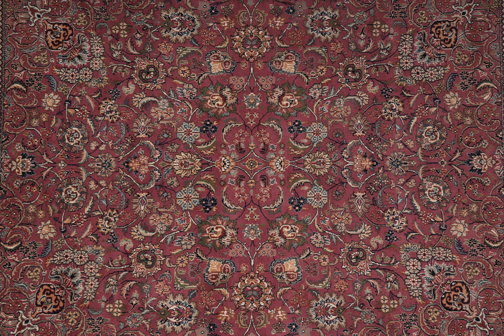 An ornate traditional oriental rug with a dense floral and vine pattern in deep red, burgundy, beige, and navy blue.