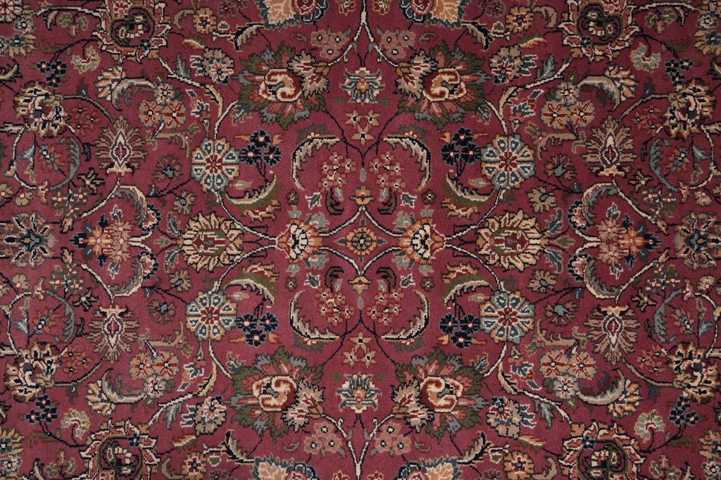 A close-up of an ornate floral patterned rug with a deep burgundy red background and intricate motifs in beige, blue, green, and brown.