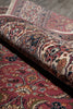 Load image into Gallery viewer, A close-up of a rolled traditional patterned rug showing its intricate floral and paisley design in red, beige, blue, and brown tones.