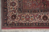 Load image into Gallery viewer, A close-up of an ornate traditional area rug corner, showing detailed floral and vine motifs in deep red, beige, navy blue, and rust tones, with cream fringe visible at the bottom.