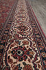 Load image into Gallery viewer, A close-up view of a traditional oriental rug with an intricate floral and medallion pattern in red, beige, navy, and brown, laid out on a gray floor.