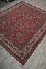 Load image into Gallery viewer, A traditional oriental area rug with a deep red field, intricate floral motifs, and a detailed border, shown laid out on a gray wood-look floor.