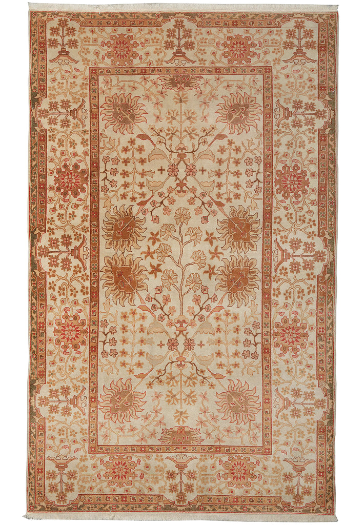 A rectangular vintage-style area rug with a cream background and intricate floral motifs in terracotta, rust, and muted orange, framed by a detailed border.
