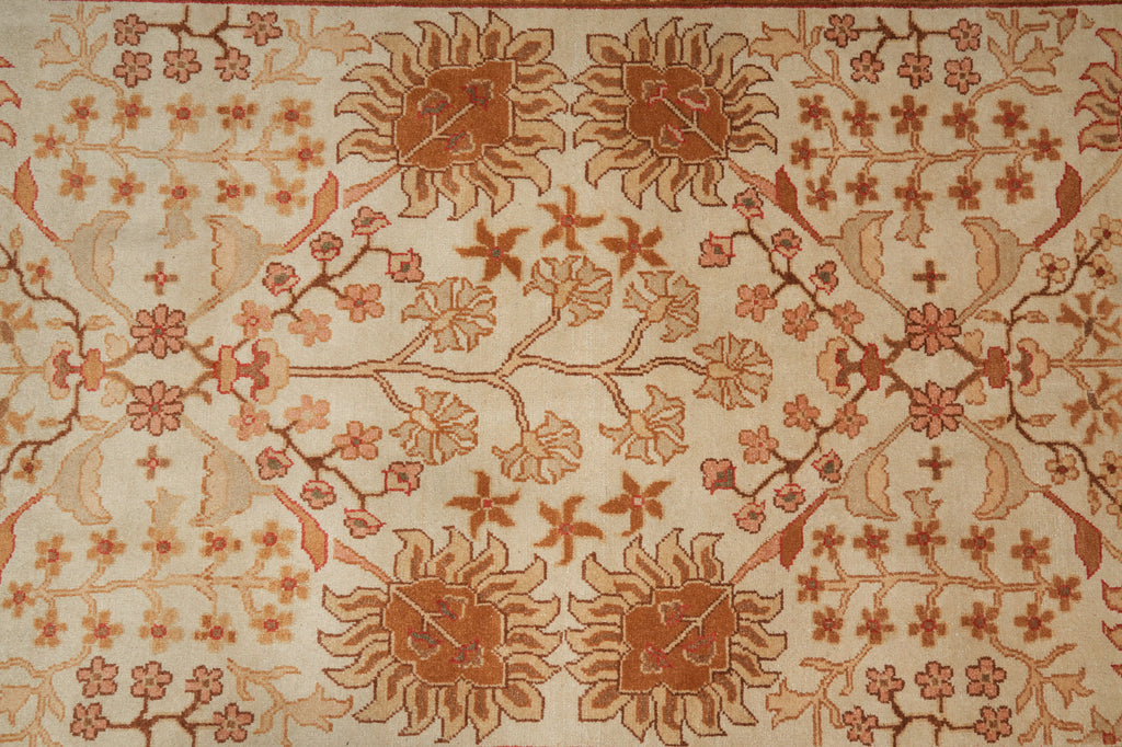 A close-up of a woven textile or rug pattern with a cream background and rust-brown floral motifs, including sunflower-like centers and small blossoms arranged in a repeating design.
