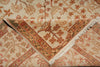 Load image into Gallery viewer, A close-up of a folded area rug with a traditional floral pattern in beige, rust orange, and brown tones, showing the woven texture and fringed edges.