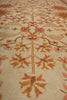 Load image into Gallery viewer, A close-up of a traditional patterned area rug with a warm cream background and floral motifs in rust orange, terracotta, and brown.