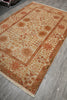 Load image into Gallery viewer, A rectangular area rug with a traditional floral pattern in beige, rust orange, and brown, laid out on a gray wood-look floor.