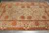 Load image into Gallery viewer, A rectangular area rug with a traditional floral and geometric pattern in rust orange, terracotta, and beige on a gray tiled floor.