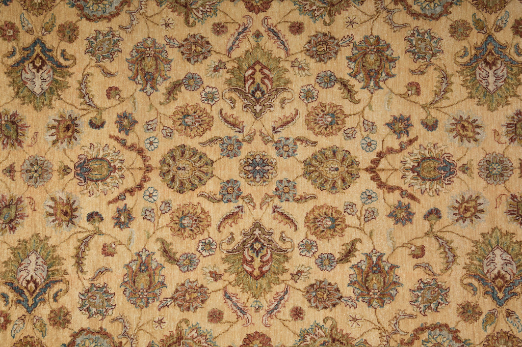 A close-up of an ornate floral patterned rug or textile with a warm beige background and repeating medallion motifs in muted blue, brown, green, and rust tones.