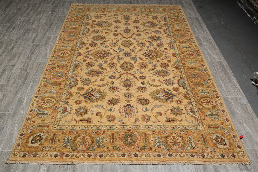 A large rectangular area rug with an intricate traditional floral and medallion pattern, laid out on a gray wood-plank floor.