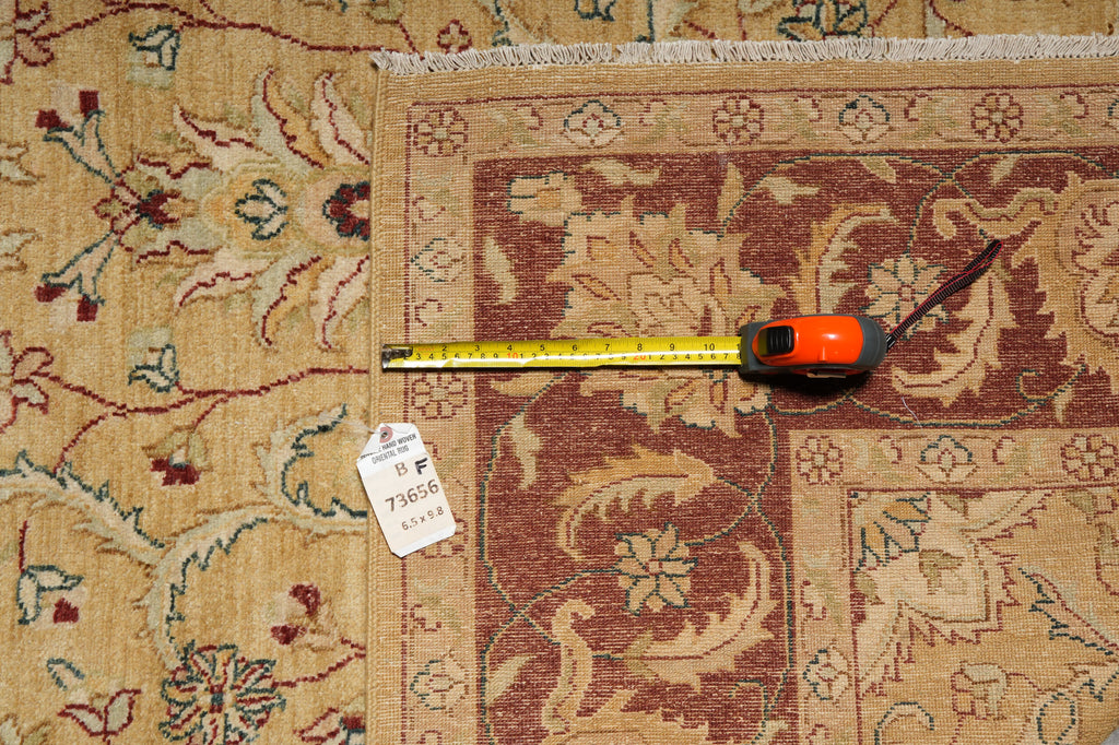 A close-up of a patterned area rug with a tape measure laid across it and a white tag attached, showing the rug's dimensions and design details.