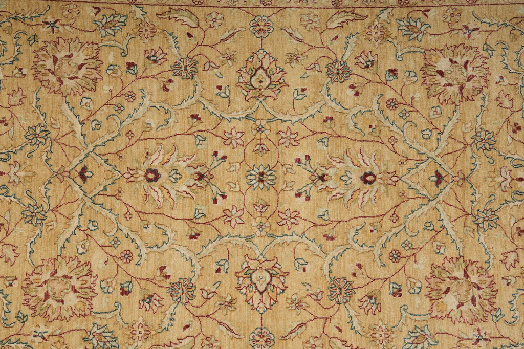 A close-up of an ornate floral patterned rug with a warm beige background and intricate vine motifs in muted red, blue, and green.