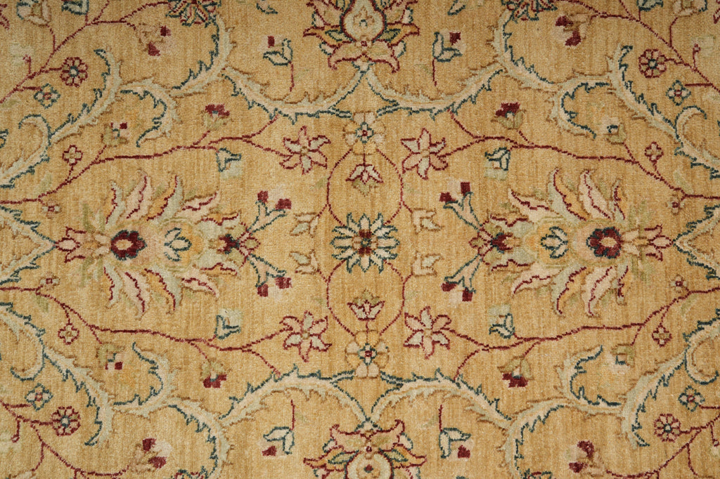 A close-up of an ornate floral patterned rug with a warm beige background and intricate vine motifs in muted red, blue, and cream.
