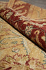 Load image into Gallery viewer, A close-up of a rolled area rug showing its traditional floral pattern in warm beige, rust red, and muted green tones.