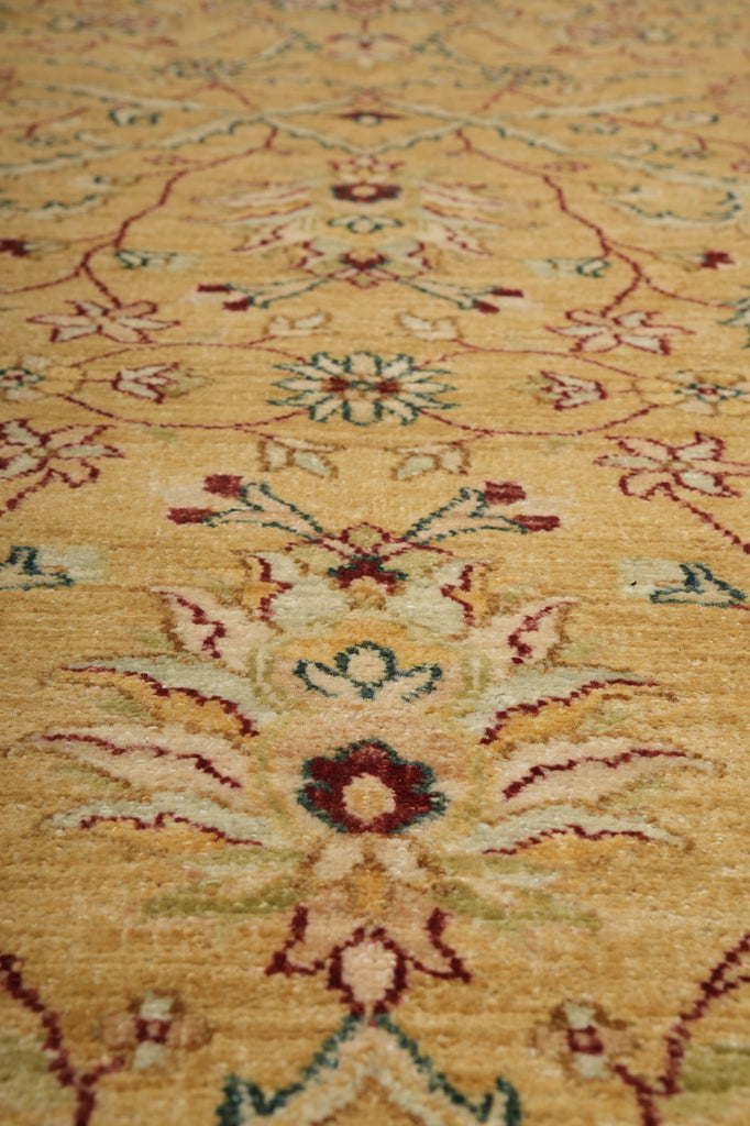 Close-up of a traditional patterned rug with a warm beige background and floral motifs in muted red, green, and cream.