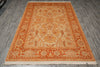 Load image into Gallery viewer, An oriental-style area rug with a traditional floral and medallion pattern, featuring a warm orange border and cream center, laid out on a gray wood-look floor.