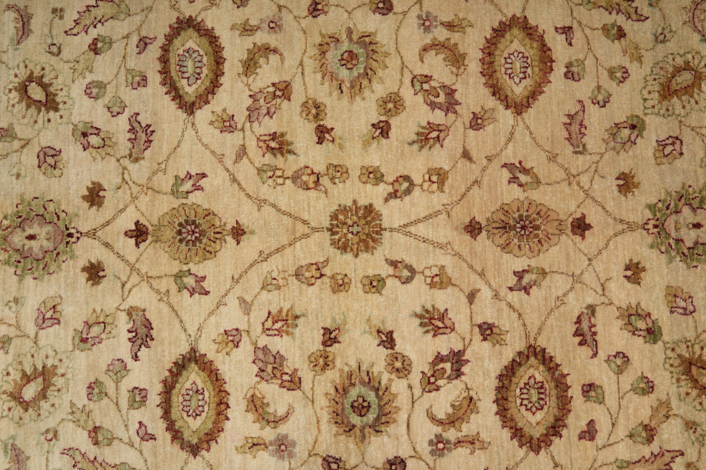 A close-up of an ornate woven textile or rug pattern with a beige background and detailed floral motifs in muted brown, dusty rose, and olive green.