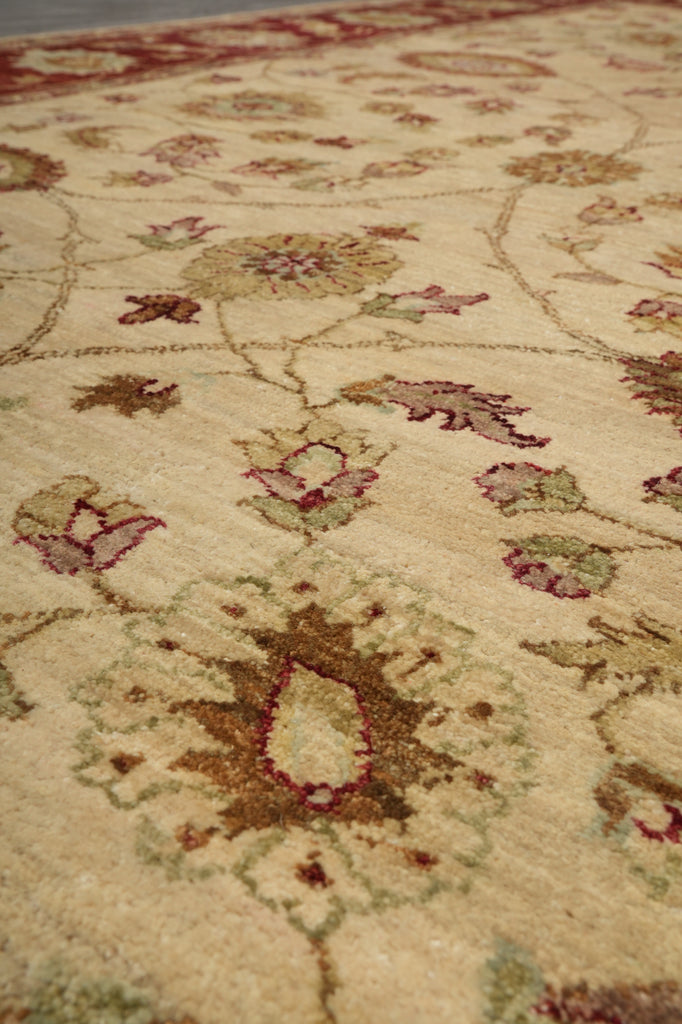Close-up of a traditional patterned area rug with a cream base and floral motifs in muted red, green, and brown tones.