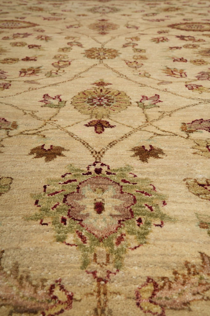 A close-up view of an ornate area rug with a traditional floral and medallion pattern in beige, muted green, and dusty rose tones.
