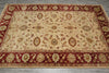 Load image into Gallery viewer, A rectangular area rug with an ornate floral and medallion pattern, featuring a cream center field, deep red borders, and muted green accents, laid out on a gray tiled floor.