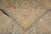 Load image into Gallery viewer, A close-up of a folded area rug showing its intricate traditional pattern in muted beige, dusty blue, and gray tones.