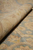 Load image into Gallery viewer, A close-up of a rolled area rug showing its plush pile and traditional floral pattern in beige, light blue, and muted yellow tones.