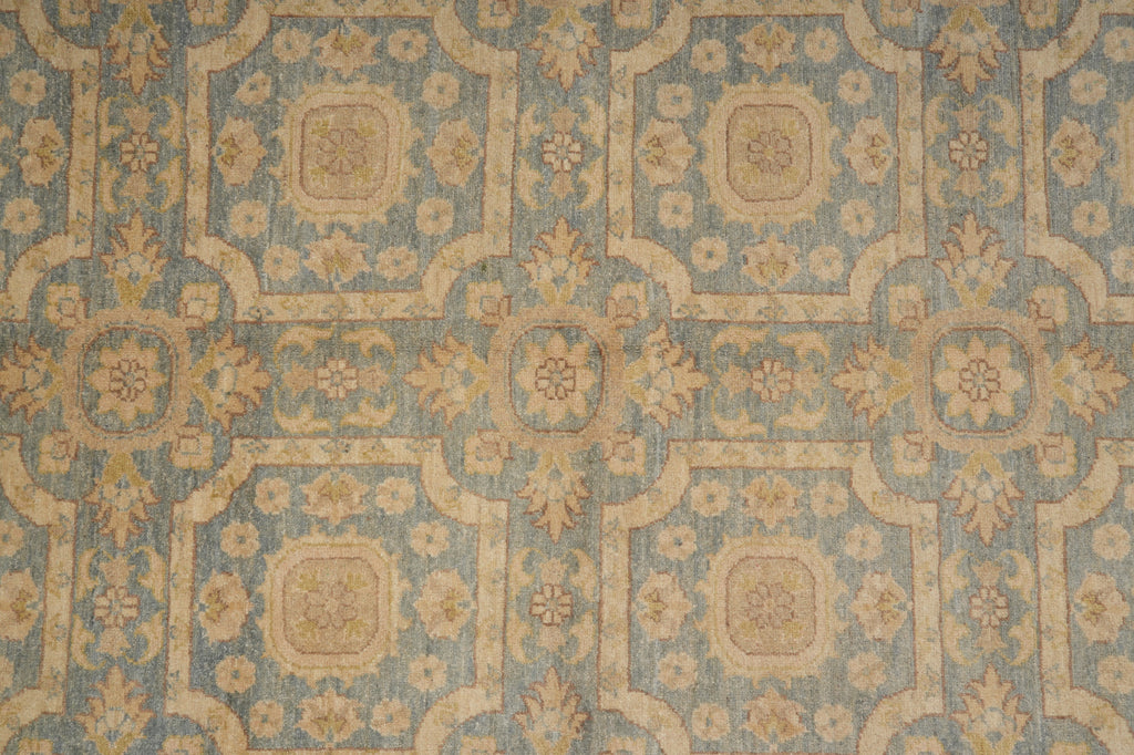 A close-up of a vintage-style patterned textile or wallpaper featuring a muted blue-gray background with beige and tan floral motifs and geometric borders.