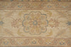 Load image into Gallery viewer, A close-up of a traditional area rug featuring a central floral medallion in muted beige, tan, dusty blue, and ochre yellow tones.