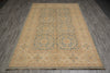Load image into Gallery viewer, A rectangular area rug with a traditional medallion pattern in beige, muted blue, and tan, laid out on a gray wood-plank floor.