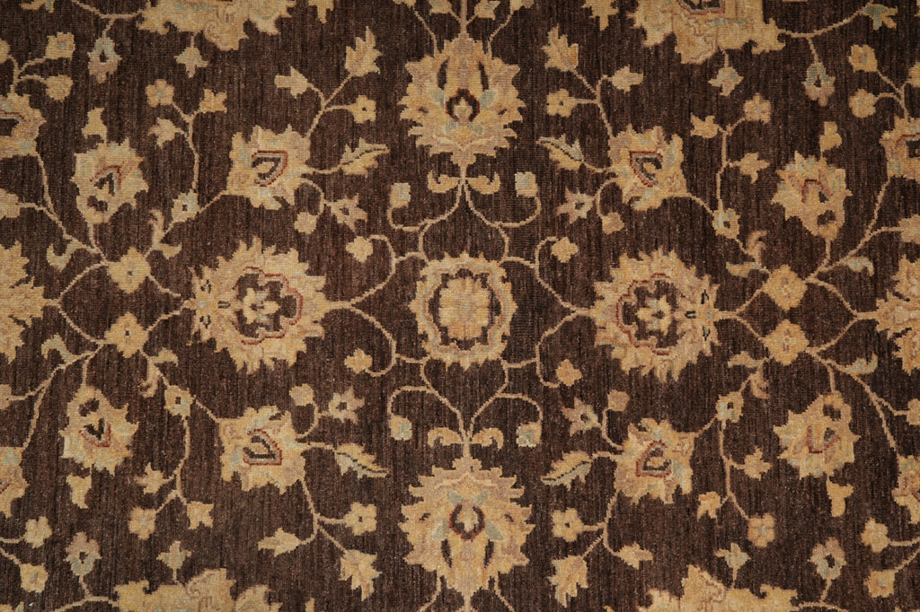 A close-up of a dark brown rug with a beige floral and vine pattern.