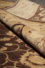 Load image into Gallery viewer, A close-up of a patterned area rug with a rolled section showing the pile and design details in beige, brown, and cream tones.