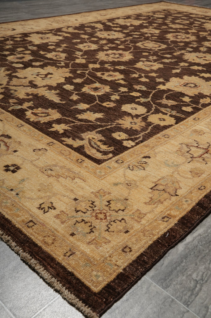 A traditional oriental-style area rug with a dark brown central field and a beige border, laid out on a gray tiled floor.