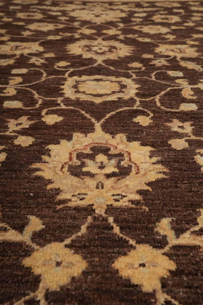 A close-up of a traditional patterned rug with a dark brown background and beige floral motifs.