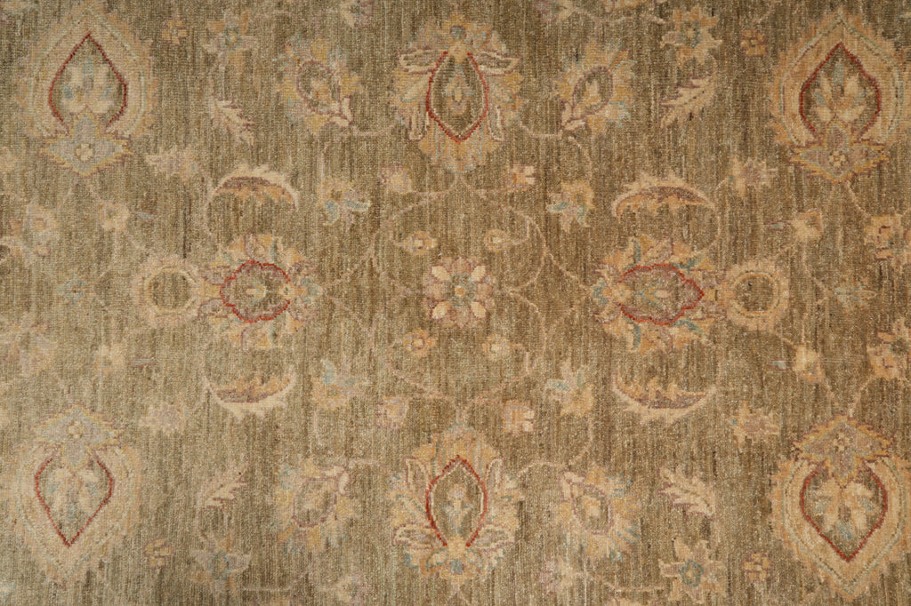 A close-up of a textured area rug featuring a traditional floral and medallion pattern in muted beige, brown, and dusty red tones.